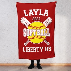 May include: Red personalised softball blanket with the name Layla, the year 2024, the words "Softball" and "Liberty HS" in white text, and a yellow softball with red stitching and two crossed bats.
