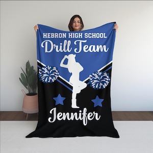May include: A blue and black fleece blanket with the text "Hebron High School Drill Team" and the name "Jennifer". The blanket features a white silhouette of a cheerleader with pom-poms.
