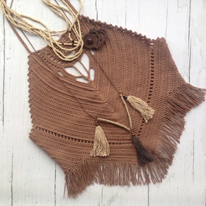Könnte beinhalten: Ein braunes Häkeltop mit Fransen. Das Top hat einen V-Ausschnitt und ein Häkeldesign.