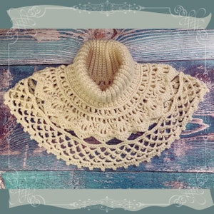 May include: A cream-coloured, handmade crochet cowl featuring a ribbed turtleneck and a decorative, openwork lace edge. The cowl is displayed on a rustic, weathered wooden surface, highlighting its intricate design and texture.