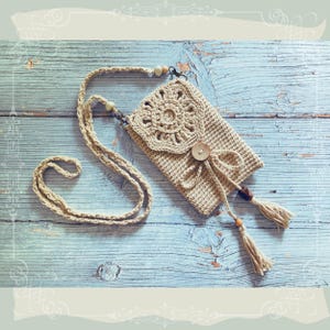 Puede incluir: Bolso bandolera de crochet beige con diseño floral en la solapa. El bolso cuenta con cierre de botón de madera, correa larga y borlas decorativas. El bolso está hecho de hilo suave y texturizado.