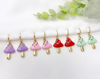 May include: A set of eight gold hoop earrings with mushroom charms. The mushrooms are decorated with colorful rhinestones and come in purple, pink, red, and green.