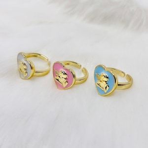 Puede incluir: Tres anillos de oro en forma de coraz&oacute;n con un dise&ntilde;o de &aacute;ngel. Los anillos son de color blanco, rosa y azul.