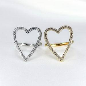 Puede incluir: Dos anillos en forma de coraz&oacute;n con un contorno de piedras transparentes. Un anillo es de plata y el otro es de oro.