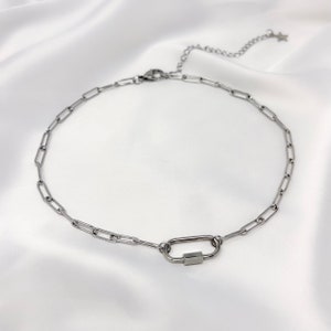 May include: A silver chain necklace with a silver carabiner clasp.