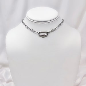 May include: A silver chain necklace with a silver oval clasp.