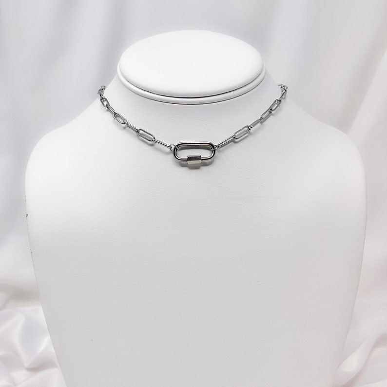 May include: A silver chain necklace with a silver oval clasp.