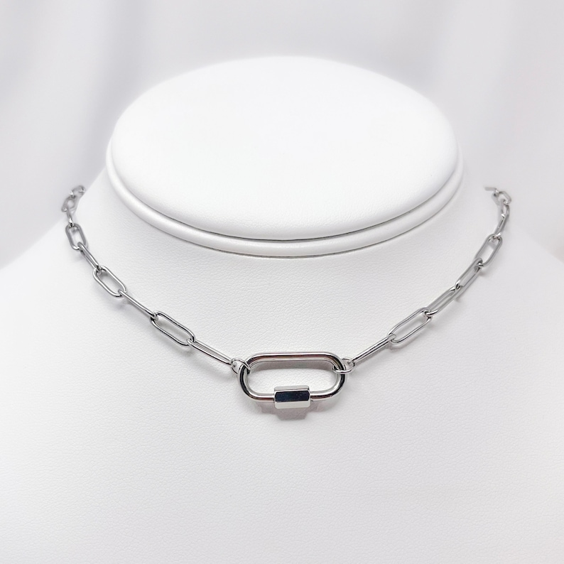 May include: A silver chain necklace with a silver oval-shaped clasp.