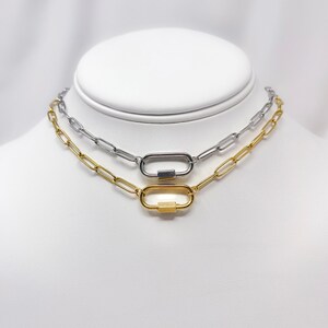 May include: Two silver and gold chain necklaces with oval-shaped clasps. The necklaces are layered on a white mannequin.
