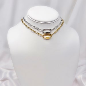May include: Two gold and silver chain necklaces with a clasp closure. The necklaces are layered on a white mannequin.