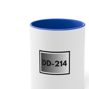 May include: White ceramic mug with a blue rim. The mug has a black and gray rectangle with the text "DD-214" printed on it.
