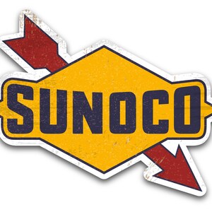 May include: A vintage-style Sunoco petrol station sign with a yellow hexagon shape and a red arrow pointing to the right. The text "SUNOCO" is in blue letters on the hexagon.