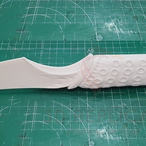 May include: A white plastic knife with a textured handle. The handle has a pattern of small circles.