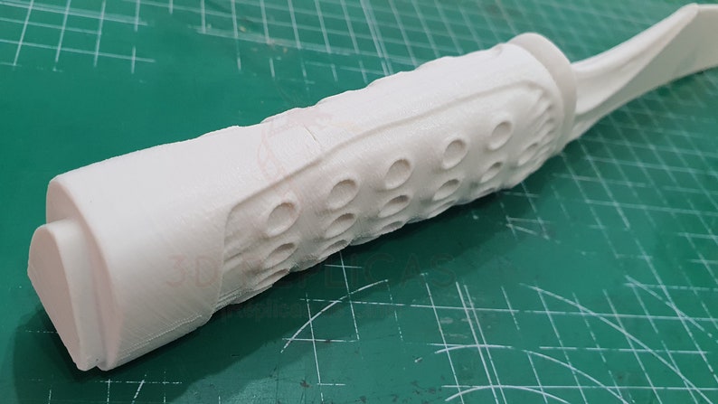May include: White plastic handle with a textured grip and a series of small holes. The handle is part of a larger object, possibly a tool or a weapon.