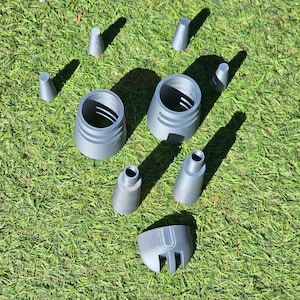 May include: A set of gray plastic 3D printed parts for a model rocket. The parts include a nose cone, a body tube, and a fin set.