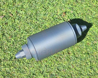 以下が含まれることがあります： グレーのプラスチック製のボトルで、ノズルとリブ状のテクスチャがあります。ボトルは緑の芝生の上に置かれています。