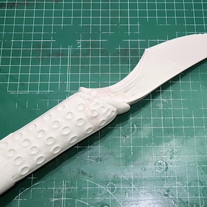 May include: White plastic prop knife with a textured handle and a curved blade.