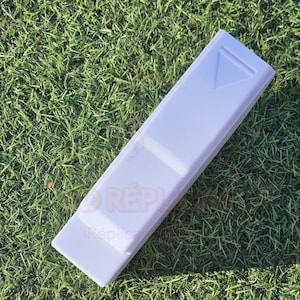 May include: A white plastic mold for making soap bars. The mold has a rectangular shape with a triangular indentation on the top.