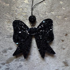 Peut inclure: Un n&oelig;ud en paillettes noires avec un accent de perles noires sur une ficelle. Le n&oelig;ud est un &eacute;l&eacute;ment d&eacute;coratif.