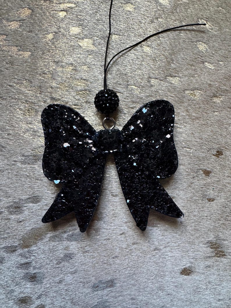 Peut inclure: Un n&oelig;ud en paillettes noires avec un accent de perles noires sur une ficelle. Le n&oelig;ud est un &eacute;l&eacute;ment d&eacute;coratif.