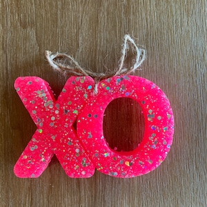 May include: Pink glitter XO ornament with a twine hanger.