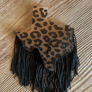 May include: A brown and black leopard print Texas shaped resin ornament with black fringe.
