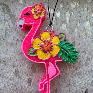 May include: Pink flamingo ornament with yellow and orange flowers and green leaves. The flamingo is standing on one leg and has a black cord attached to it.