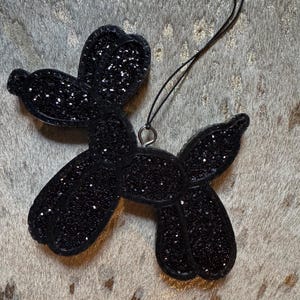 May include: Black glitter balloon dog ornament with a black string for hanging.
