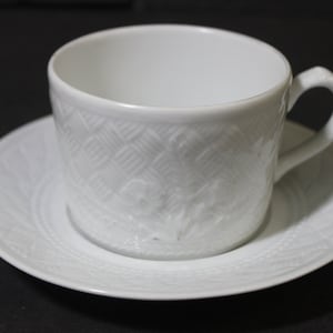 Puede incluir: Juego de taza y platillo de porcelana blanca con un diseño floral en relieve.
