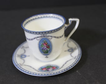 May include: A white teacup and saucer with a blue and white floral pattern. The cup has a handle and the saucer has a scalloped edge.