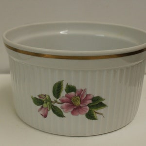 May include: White ceramic baking dish with a gold rim and a floral design featuring a pink flower and green leaves.