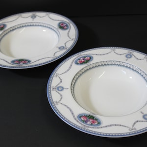 Pode incluir: Duas tigelas de sopa brancas com desenhos florais azuis e brancos. As tigelas têm uma borda ondulada e uma borda larga.