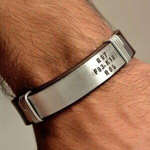May include: A brown leather bracelet with a silver metal band engraved with the text "R 97 F03-K10 R 05".