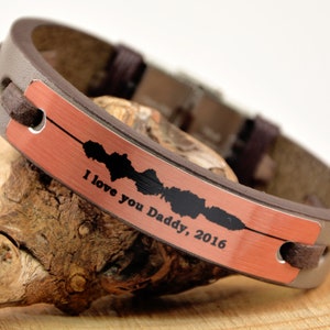 Puede incluir: Una pulsera de cuero marr&oacute;n con una placa de color cobre. La placa tiene un dise&ntilde;o de onda de sonido y el texto "I love you Daddy, 2016". La pulsera est&aacute; sobre una superficie de madera.