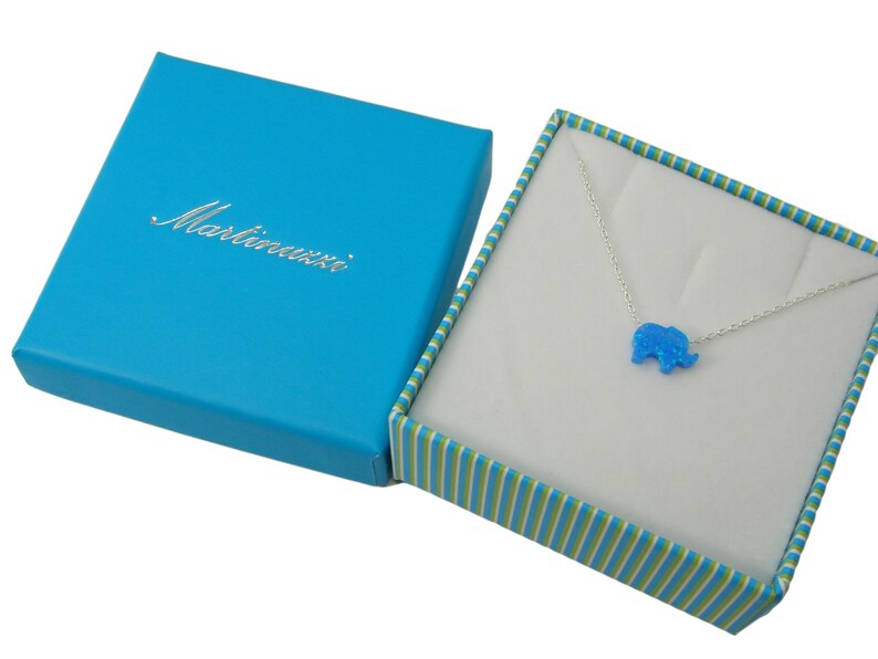 May include: A blue opal elephant pendant necklace in a blue and green striped gift box. The box is labeled "Martinauzzi".