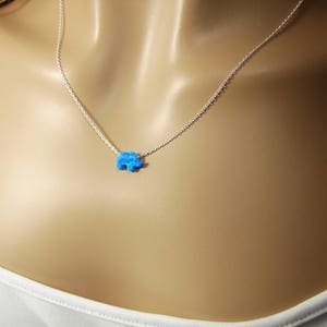 May include: A silver chain necklace with a small blue opal elephant pendant.