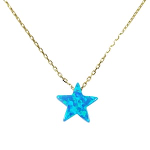 May include: A gold-colored chain necklace with a blue star-shaped pendant. The star has a textured, opalescent appearance, with shades of blue and turquoise. The necklace is displayed against a white background.