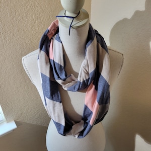 May include: A pink and blue striped infinity scarf. The scarf is made of a soft, stretchy fabric and is perfect for adding a pop of color to any outfit.