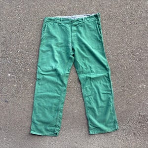 Peut inclure: Un pantalon vert vif doté d'une coupe droite, d'une fermeture à boutons et de poches latérales. Le pantalon présente une ceinture visible avec des passants et une doublure intérieure de couleur claire au niveau du bord supérieur du vêtement.