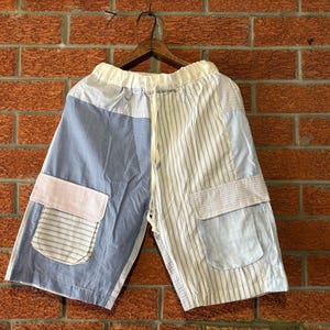 May include: Blue and white striped patchwork shorts with a pink pocket and a drawstring waist.
