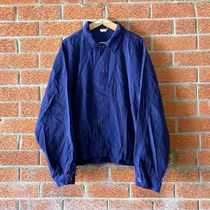 Könnte beinhalten: Eine einfarbige, marineblaue Langarmjacke mit spitzem Kragen, einer durchgehenden Knopfleiste mit passenden dunklen Knöpfen und geknöpften Manschetten. Das Kleidungsstück hat eine strukturierte Passform mit sichtbaren Nähten an den Ärmeln.
