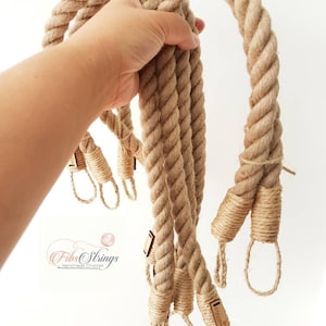 May include: A collection of thick, natural-colored rope handles, held in a hand against a white background. Each handle is tightly wound and features decorative wrapped ends with small tags. The logo "Fibs Strings Handmade Crochet" is visible.