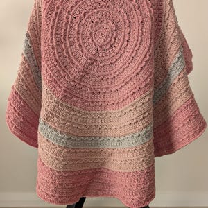 May include: A pink crocheted baby blanket with a circular design and a gray and pink border.
