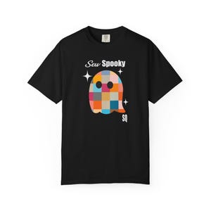 May include: Black t-shirt with a colourful, pixelated ghost design. The text reads "Sew Spooky" with the initials "SQ". The ghost design incorporates squares of orange, blue, pink, and yellow.