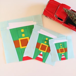 May include: Three different sizes of felt elf ornaments in green, red, and yellow. The ornaments are layered and have a white border.
