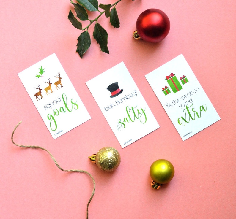 May include: Four Christmas-themed gift tags with green and white illustrations and text. The tags feature the phrases "squad goals", "bah humbug! #salty", "tis the season to be extra", and a group of reindeer.