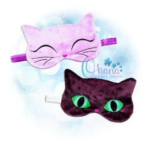 Op de afbeelding: Twee pluche oogmaskers in de vorm van een kat. Eén is paars met roze stiksels en de andere is donkerpaars met groene ogen.