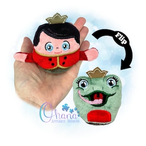 May include: A plush toy that flips from a prince to a frog. The prince has black hair, a red jacket, and a gold crown. The frog is green with a red belly and a gold crown. The word "Flip" is written on a black arrow.