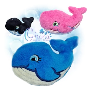 May include: Three plush whale toys in black, pink, and blue. Each whale has a white belly, a tail, and a smiling face with eyelashes. The image includes the text "Ohana Applique Designs".