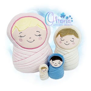 Puede incluir: Cuatro muñecos de bebé de peluche de varios tamaños. Los muñecos están envueltos en pañales y tienen caras bordadas con los ojos cerrados y la boca sonriendo. El muñeco más grande es rosa, el siguiente más grande es blanco y los más pequeños son azules y crema.